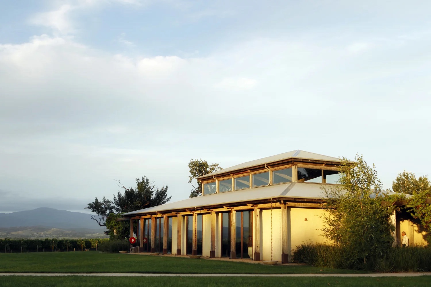 The Barn at Stones of the Yarra Valley in golden evening light, with vineyards and mountains behind